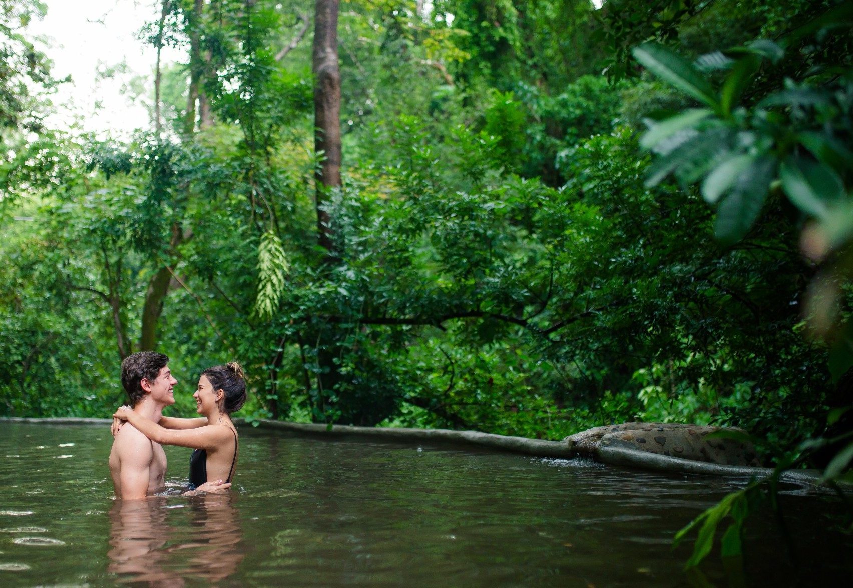 Couple relaxing together in a lush volcanic thermal pool
