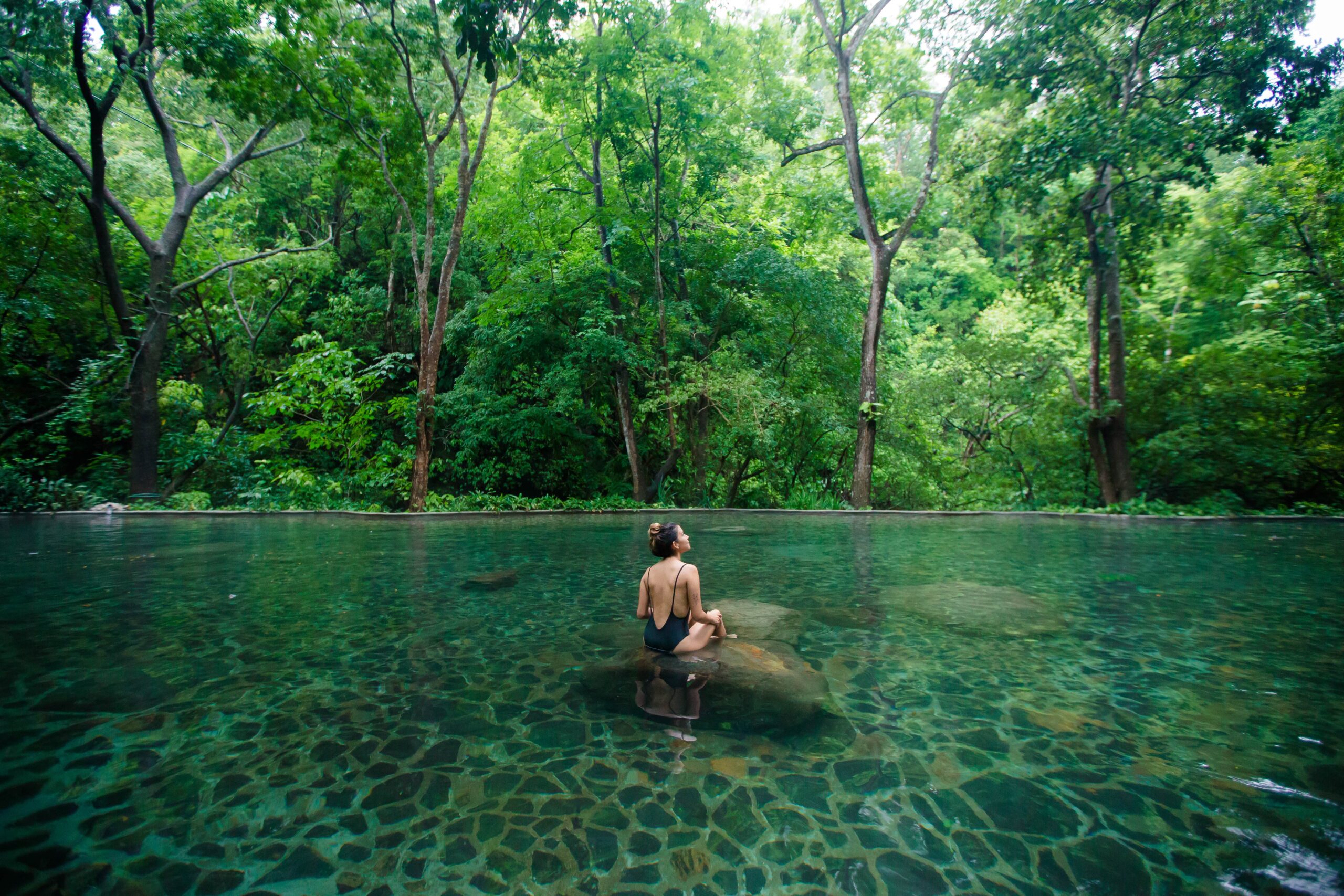 a women sitting on a rock in a pool