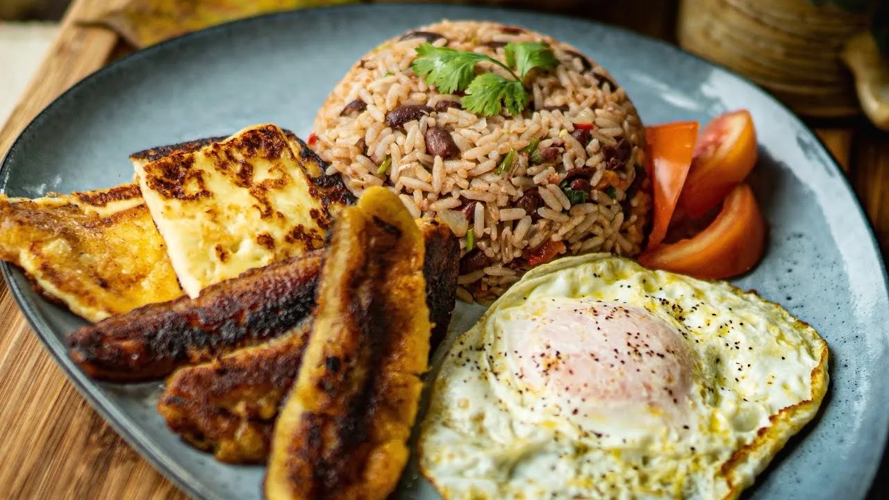 Plate with rice, fried egg, plantains, cheese, and tomatoes.
