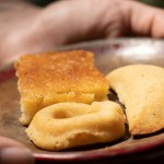 Hand holding a plate with three traditional baked goods.