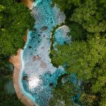 Aerial view of a mosaic pool surrounded by dense green foliage.