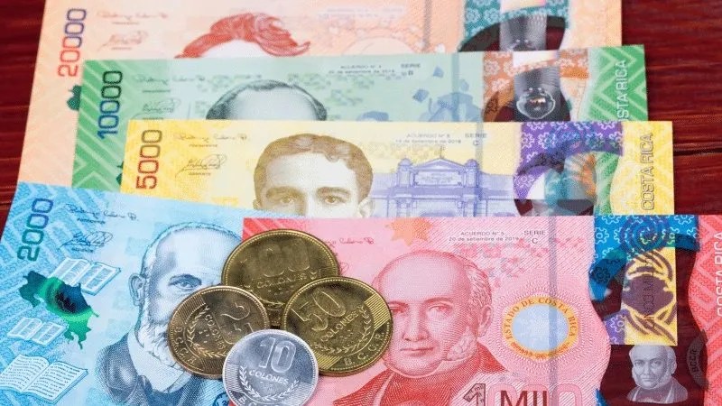 Assorted colorful banknotes and coins on a wooden surface.