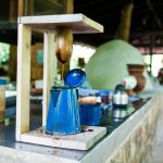 Rustic coffee setup with blue pot under wooden stand outdoors.