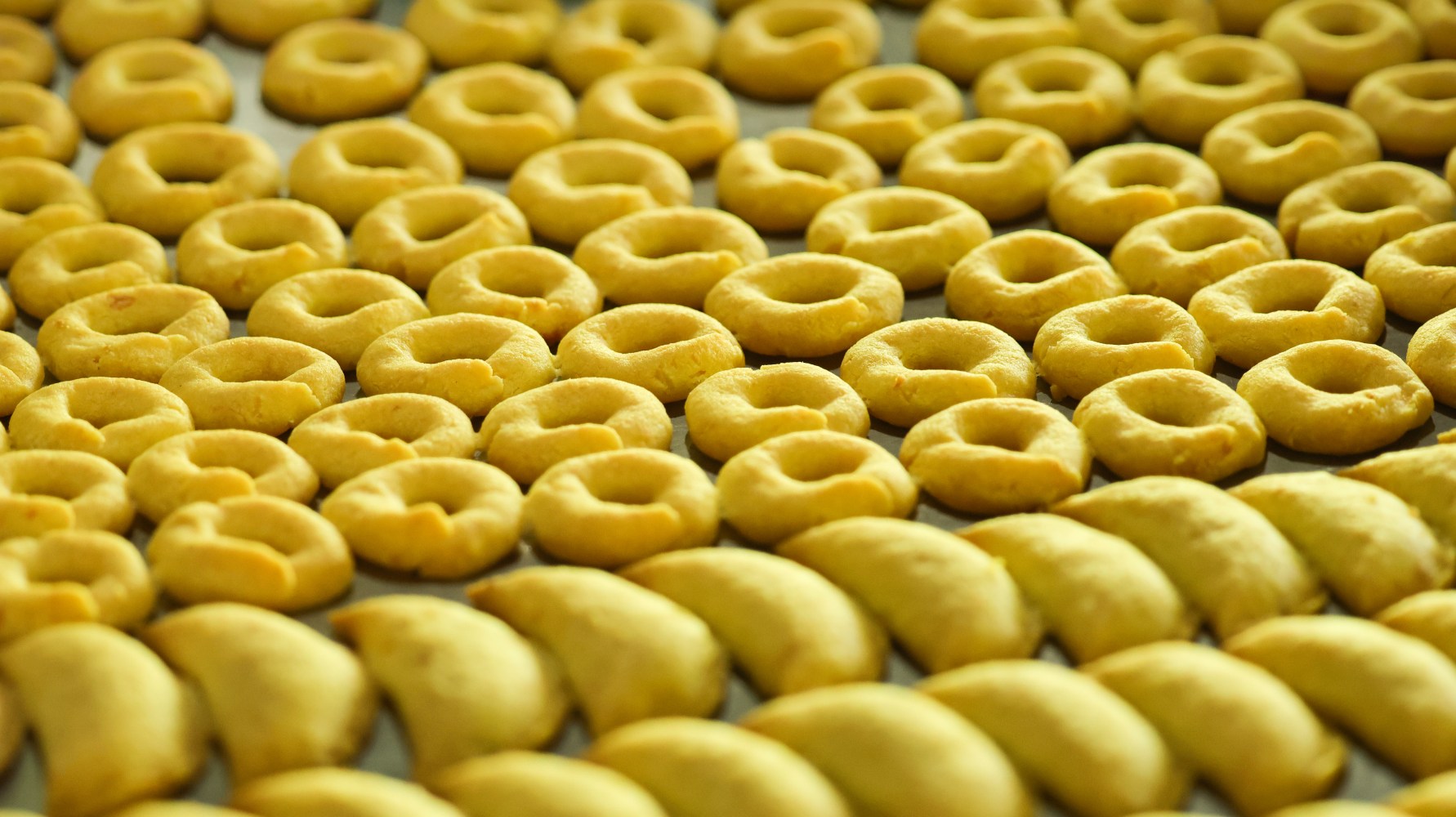 Filas de galletas en forma de anillo y de media luna en una bandeja de horno.