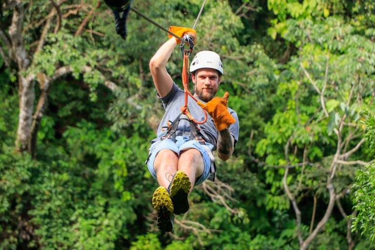 Guest ziplining through the canopy holding a stuffed toy