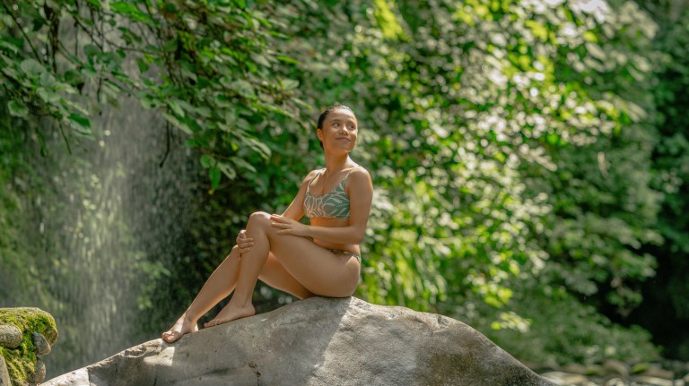 Guest relaxing by a rainforest waterfall in a bikini