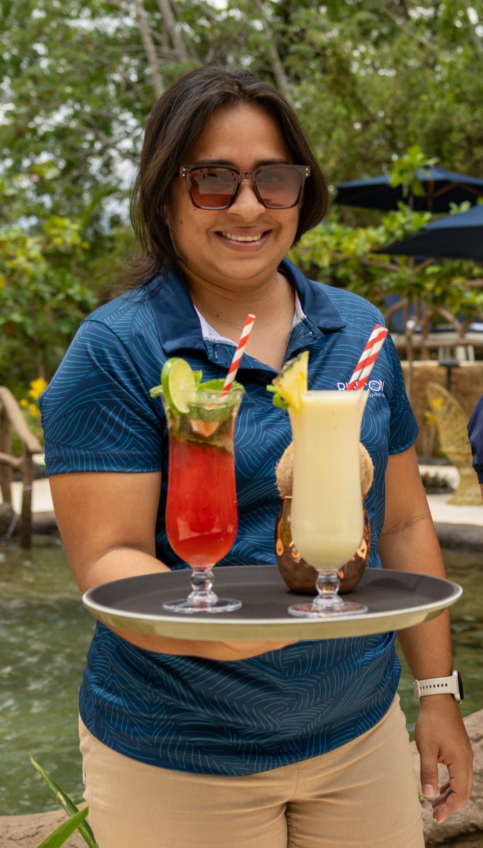 Two people holding trays with colorful drinks outdoors.