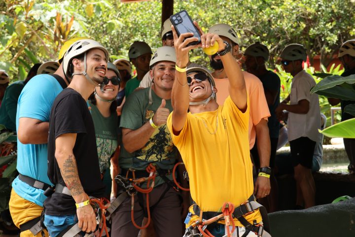 Group of people in helmets taking a selfie, wearing outdoor gear.