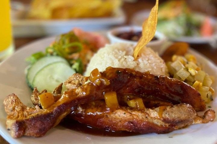 Barbecue ribs with rice, cucumber, and vegetables on a plate.